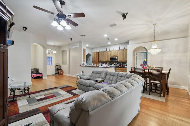 living room with light hardwood / wood-style floors and ceiling fan with notable chandelier