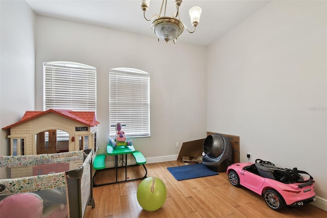 recreation room with light wood-type flooring, a chandelier, and plenty of natural light