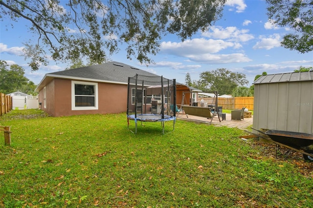 rear view of house with a patio area, a yard, a trampoline, and a storage shed