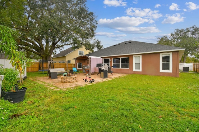 back of property with central AC unit, a patio area, a lawn, and an outdoor fire pit