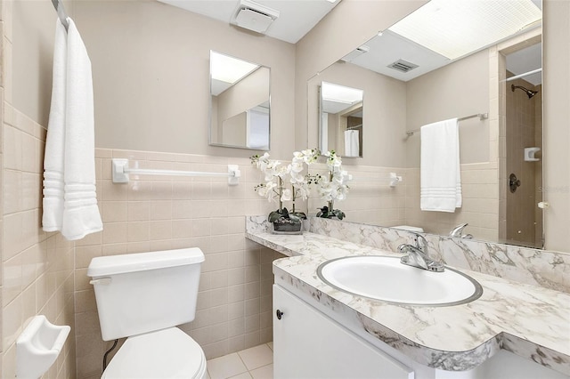 bathroom featuring vanity, toilet, tile walls, and tile patterned flooring