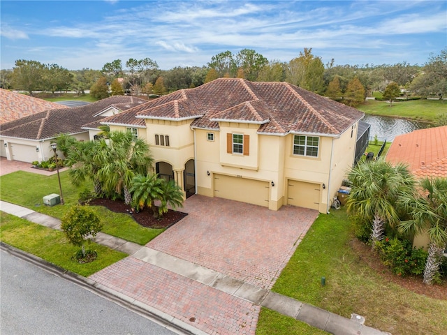 mediterranean / spanish house with a garage, a water view, and a front yard