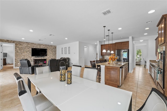 dining area with a stone fireplace, sink, and light tile patterned floors