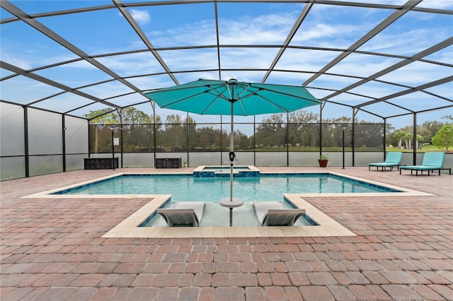 view of pool with a patio, glass enclosure, and an in ground hot tub