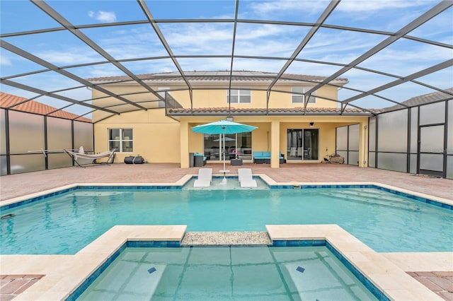 view of swimming pool with an in ground hot tub, glass enclosure, and a patio area