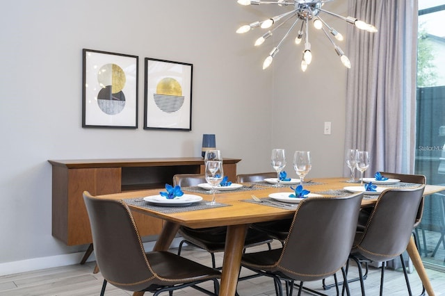 dining area with light wood-type flooring and an inviting chandelier