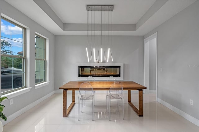 dining space featuring a tray ceiling and light tile patterned floors