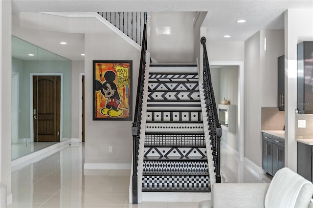 stairs featuring tile patterned flooring and a textured ceiling