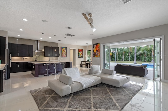 tiled living room featuring ceiling fan, sink, and a textured ceiling