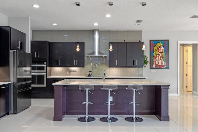 kitchen with black refrigerator, pendant lighting, and wall chimney exhaust hood