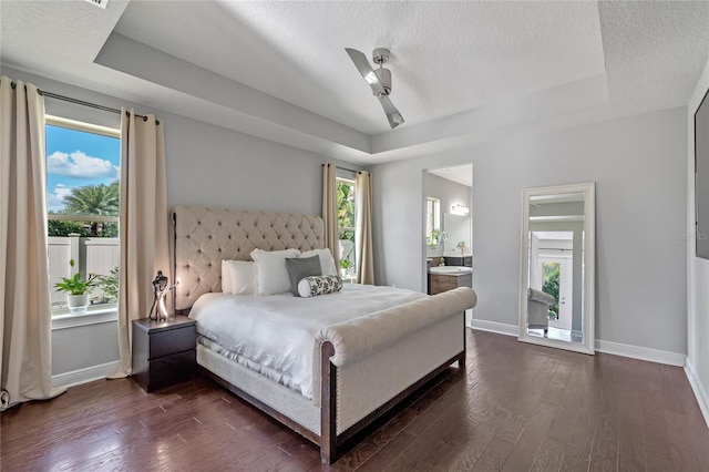 bedroom with ceiling fan, dark hardwood / wood-style floors, ensuite bath, and multiple windows