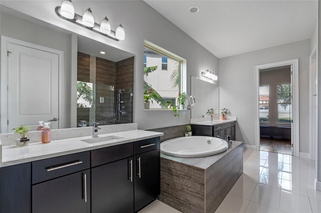 bathroom with tile patterned flooring, vanity, a tile shower, and a wealth of natural light