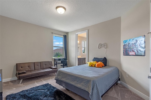 carpeted bedroom with ensuite bath and a textured ceiling