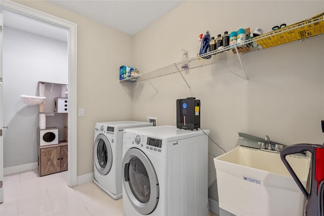 washroom featuring a textured ceiling, washer and clothes dryer, and sink