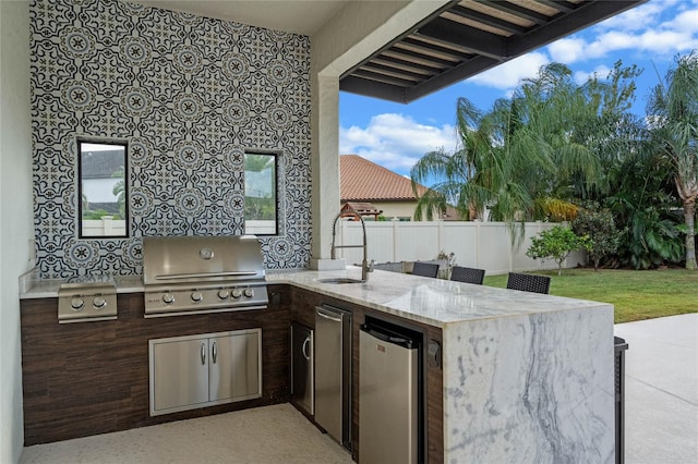 view of patio featuring a grill, an outdoor wet bar, and an outdoor kitchen