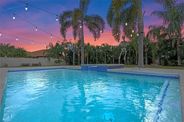 pool at dusk with an in ground hot tub