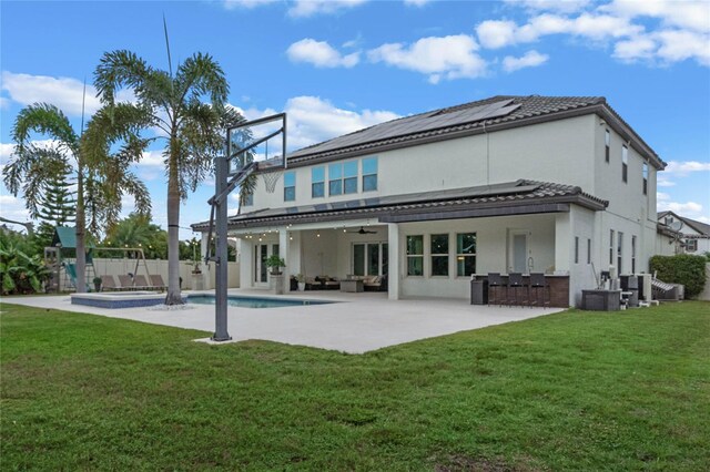 back of house with solar panels, outdoor lounge area, ceiling fan, a yard, and a patio