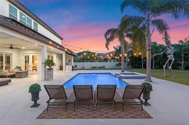 pool at dusk featuring french doors, an outdoor living space, ceiling fan, and a patio area