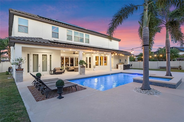 pool at dusk with an in ground hot tub, french doors, an outdoor hangout area, area for grilling, and a patio