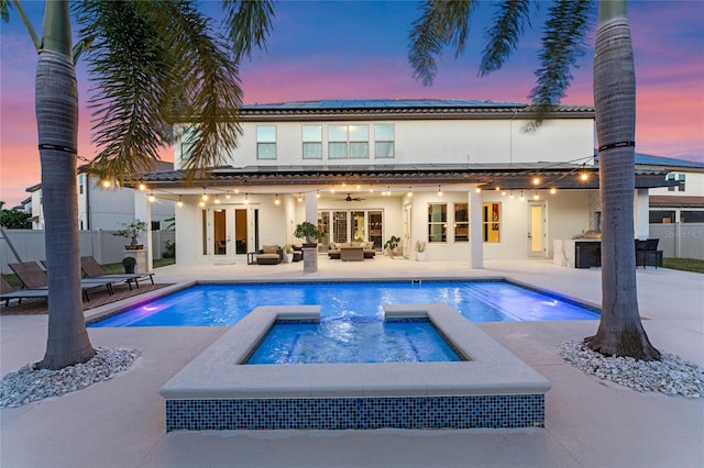 pool at dusk featuring an outdoor living space, ceiling fan, an in ground hot tub, and a patio