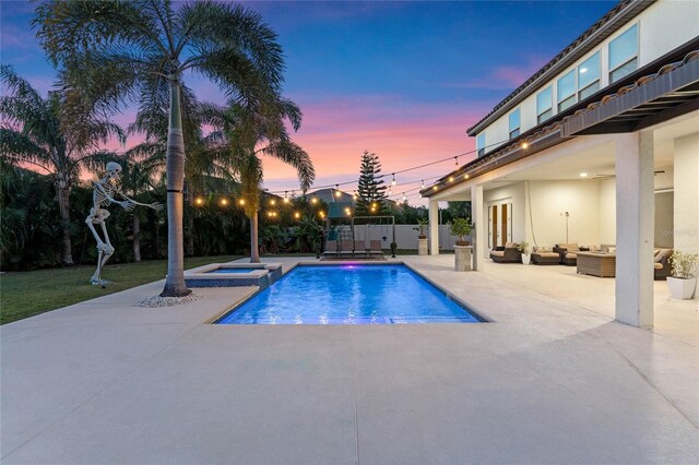 pool at dusk with an outdoor living space, an in ground hot tub, and a patio