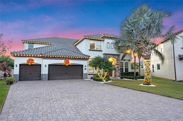 mediterranean / spanish home featuring a garage and a yard