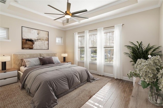 bedroom featuring a tray ceiling, ceiling fan, dark hardwood / wood-style flooring, and crown molding