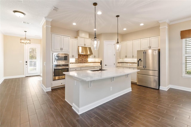 kitchen featuring stainless steel appliances, sink, white cabinets, a breakfast bar area, and an island with sink