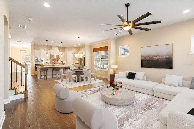 living room featuring sink and ceiling fan with notable chandelier