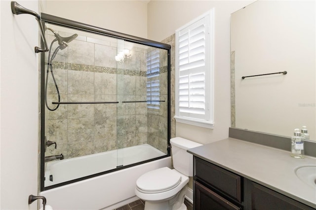 full bathroom with combined bath / shower with glass door, vanity, and toilet