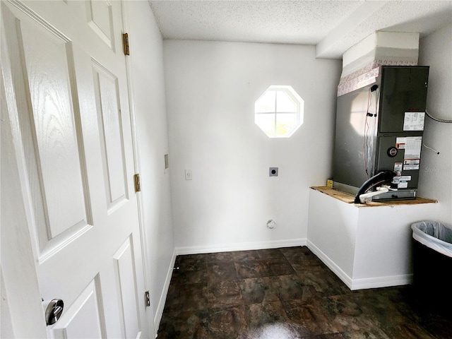 laundry area featuring heating unit, a textured ceiling, and hookup for an electric dryer