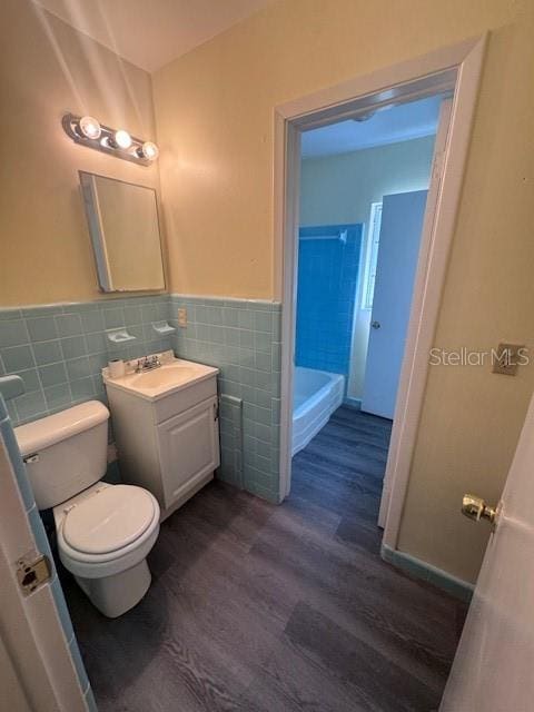 bathroom with tile walls, hardwood / wood-style floors, vanity, and toilet