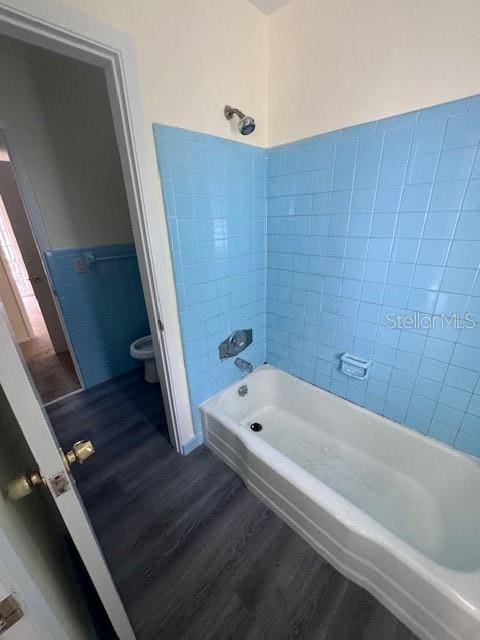 bathroom featuring toilet, tiled shower / bath, and hardwood / wood-style flooring