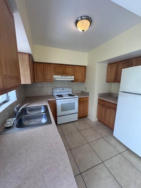 kitchen with decorative backsplash, white appliances, sink, and light tile patterned floors