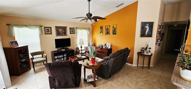 living room featuring lofted ceiling, ceiling fan, light tile patterned flooring, and a textured ceiling