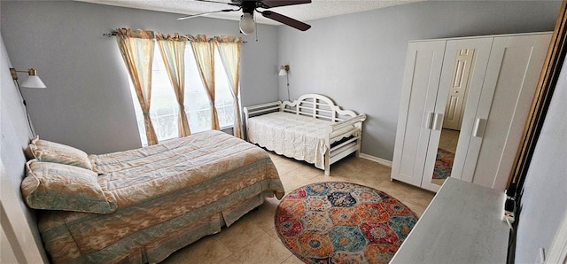 bedroom featuring ceiling fan, light tile patterned flooring, and a textured ceiling