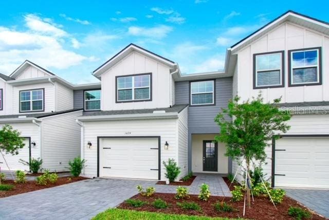 1541 Heritage Pl, Oviedo, FL 32765 - view of front of house with board and batten siding, an attached garage, and decorative driveway
