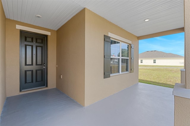 view of exterior entry with a lawn and a patio