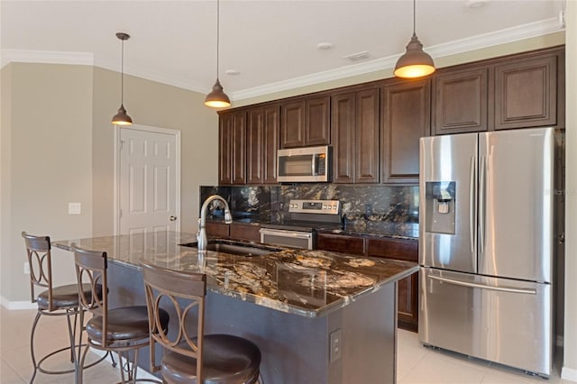 kitchen featuring appliances with stainless steel finishes, dark brown cabinetry, hanging light fixtures, sink, and dark stone countertops