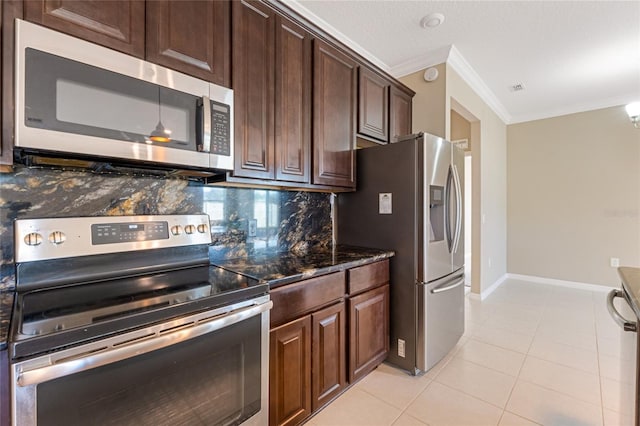 kitchen with ornamental molding, stainless steel appliances, backsplash, light tile patterned floors, and dark stone countertops