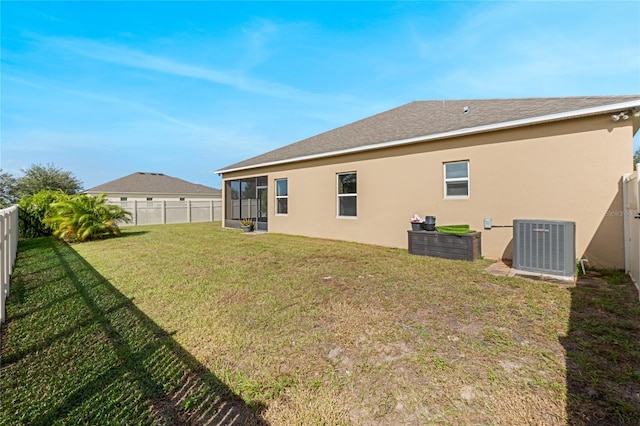 back of property featuring a sunroom, central AC, and a yard