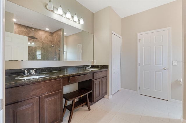 bathroom with tile patterned flooring, tiled shower, and vanity