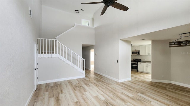 unfurnished living room featuring a high ceiling, ceiling fan, and light hardwood / wood-style floors