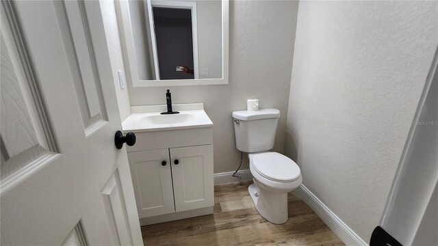 bathroom featuring a textured wall, vanity, toilet, and wood finished floors