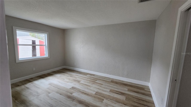 unfurnished room featuring a textured ceiling and light hardwood / wood-style floors