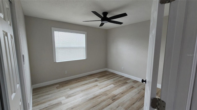 spare room featuring baseboards, ceiling fan, and light wood-style floors