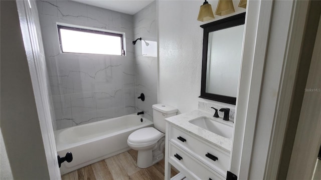 full bathroom featuring a textured wall, toilet, wood finished floors, vanity, and washtub / shower combination