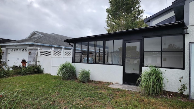 view of side of home featuring a garage, a lawn, and a sunroom