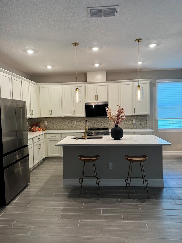 kitchen featuring appliances with stainless steel finishes, sink, hanging light fixtures, and a kitchen island with sink