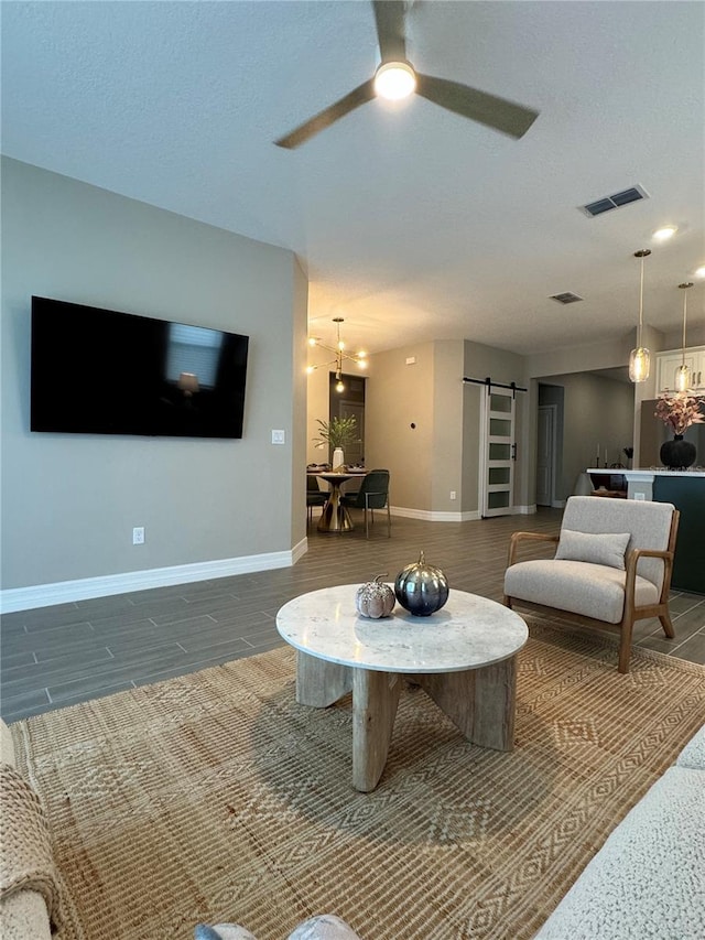 living room featuring ceiling fan, a barn door, and dark hardwood / wood-style floors